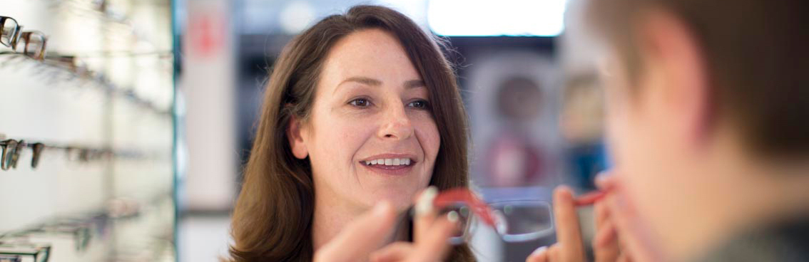 optometrist fitting glasses on patient